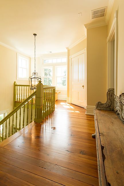 Hallway with green banister, wooden floor, and antique console table.