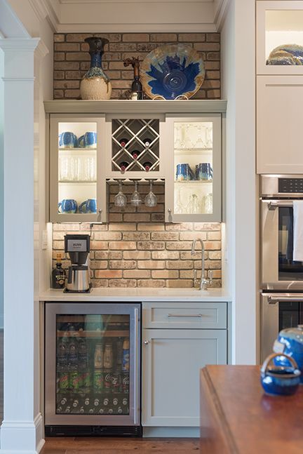 A built-in home bar with brick backsplash, wine rack, mini fridge, and cabinet for drinks.