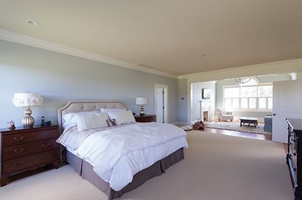 Spacious bedroom with a bed, nightstands, and sitting area with natural light.
