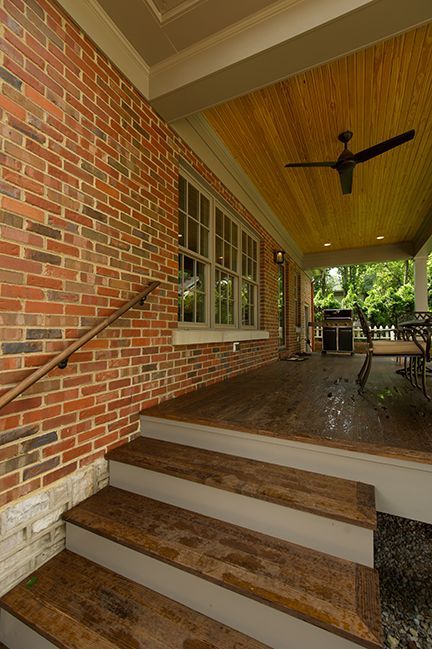 Brick steps lead to a covered porch with wooden ceiling and red brick wall.