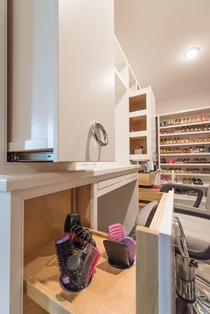 Closet with built-in vanity area. Wall-mounted cabinet, open shelves. Brushes and hair tools on wooden countertop.