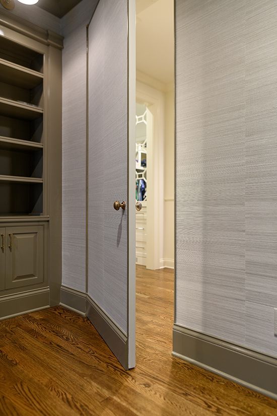 Ajar secret door with light blue wallpaper, wooden floor, and a bookcase.