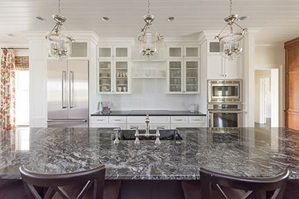 Elegant white kitchen with granite countertop, stainless steel appliances, and pendant lights.