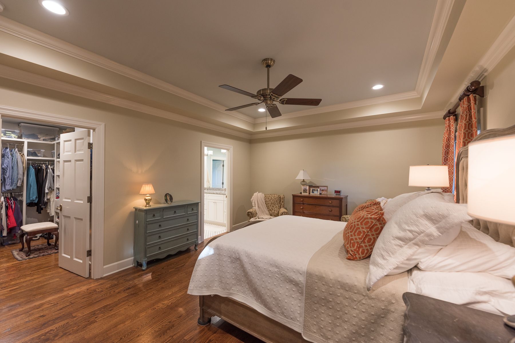 Bedroom with a bed, closet, dresser, and ceiling fan; hardwood floors.