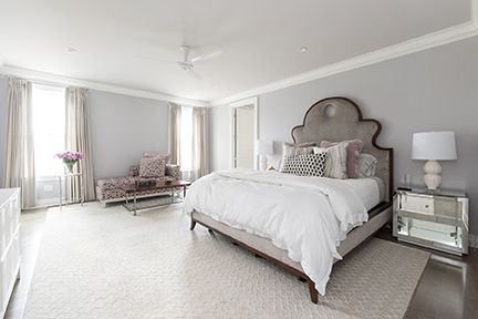 Elegant bedroom with a gray palette, including a large bed, seating area, and mirrored nightstand.