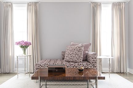 Living room with patterned chaise lounge, two windows with curtains, and coffee table.