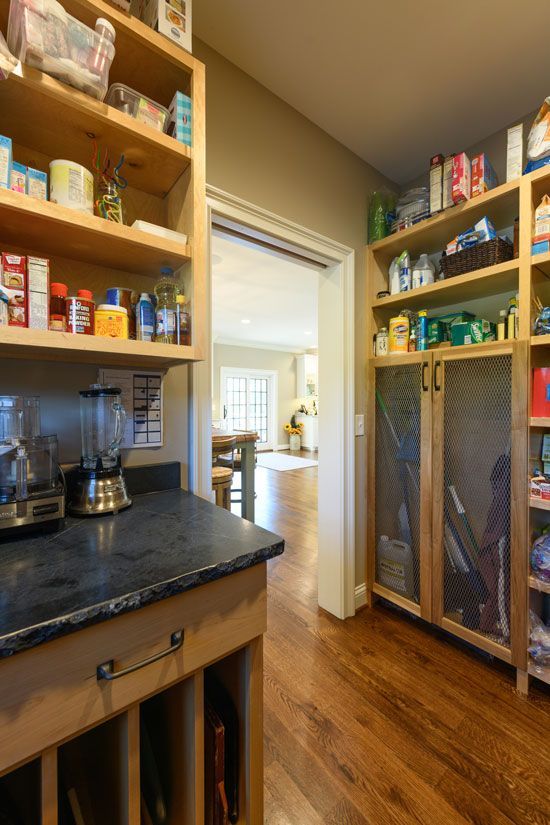 Pantry with wooden shelves stocked with food items. A counter with appliances is on the left. Doorway leads to a room.