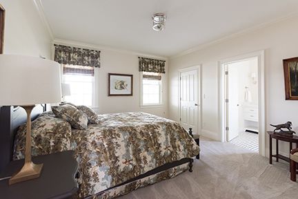 Bedroom with bed, windows, artwork, and open doorway to a bathroom.