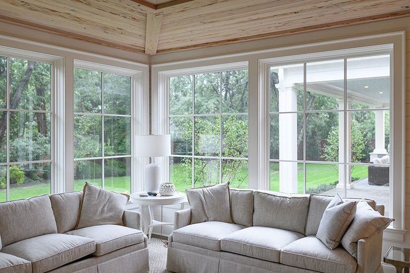Living room with large windows overlooking a green yard and white sofas.