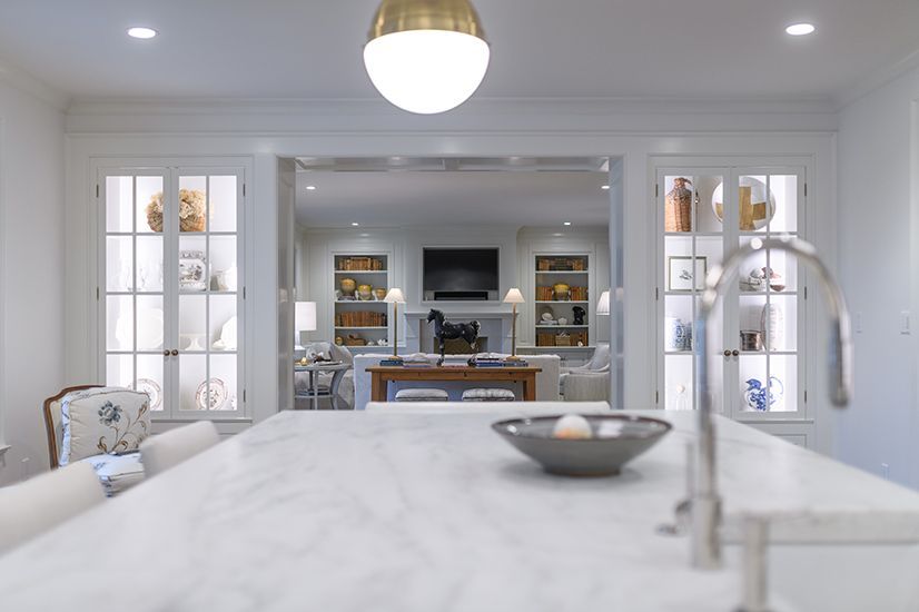 Kitchen island with sink, view through doorway to living room with fireplace, built-in shelves.