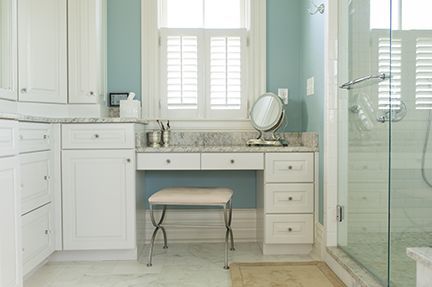 White bathroom with vanity, light blue walls, and glass shower.