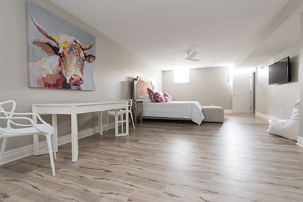 A spacious bedroom with a desk, bed, TV, and a cow painting on the wall.