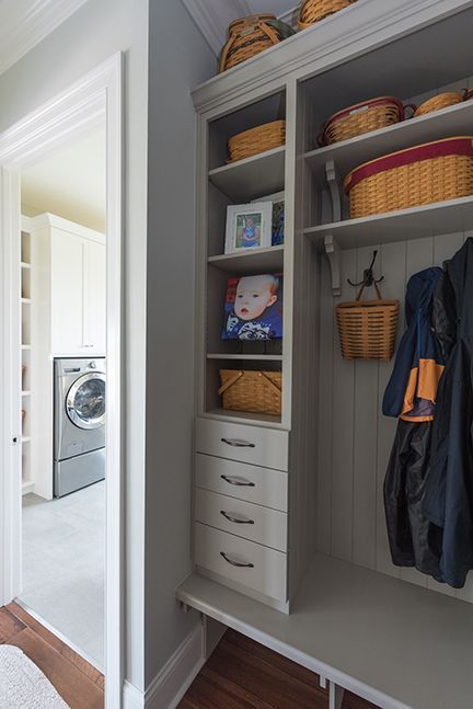 Built-in storage unit with shelves, drawers, and a bench in a home entryway. Laundry room visible in the background.