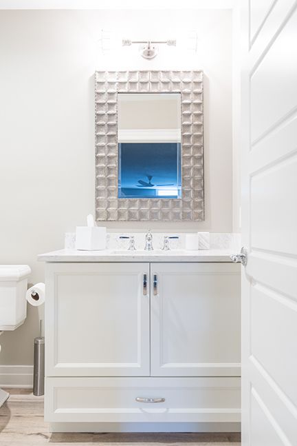 White bathroom vanity with mirror and door, neutral color scheme.