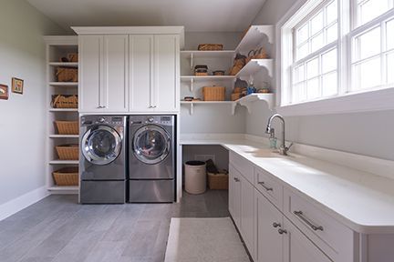 Laundry room with white cabinets, gray appliances, and a large window.