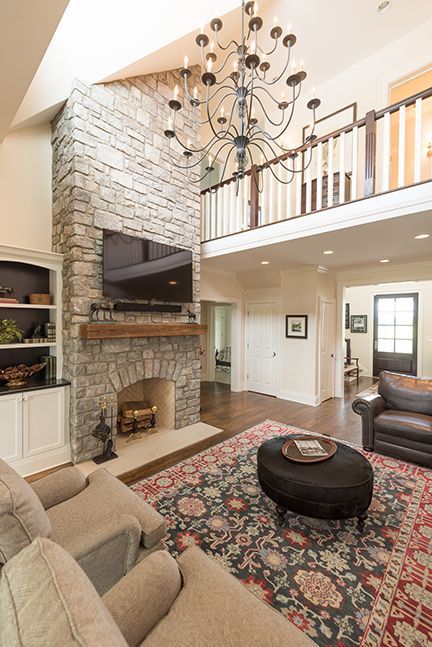Living room with stone fireplace, chandelier, seating area, and a rug.