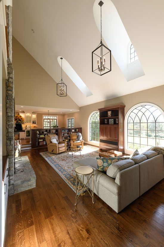 Living room with vaulted ceiling, skylights, and dark wood floor. Includes a sofa, rug, and stone fireplace.