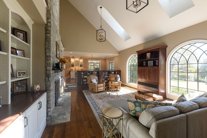 Spacious living room with stone fireplace, arched windows, and a beige couch.