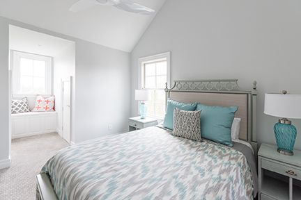 Bedroom with a bed, two nightstands with lamps, and a window seat. Walls are light gray.