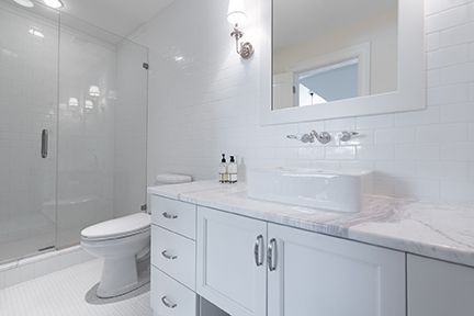White bathroom with a glass shower, toilet, vanity, and sink.