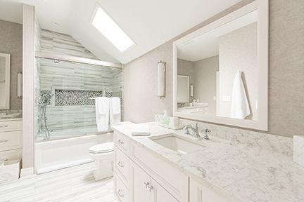 Elegant white bathroom with marble counter, shower, and large mirror.