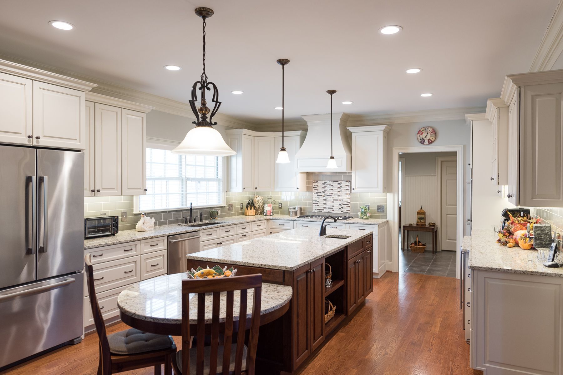 Bright kitchen with white cabinets, dark island, granite countertops, and stainless steel appliances.