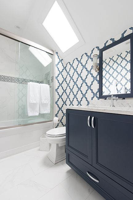 Bathroom with blue vanity, patterned blue and white tile, and a skylight.