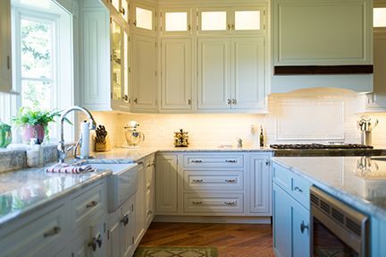 White kitchen with light cabinets, countertops, sink, and oven.