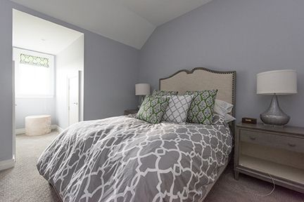 Bedroom with gray walls, bed with patterned comforter, nightstand, and pillows.