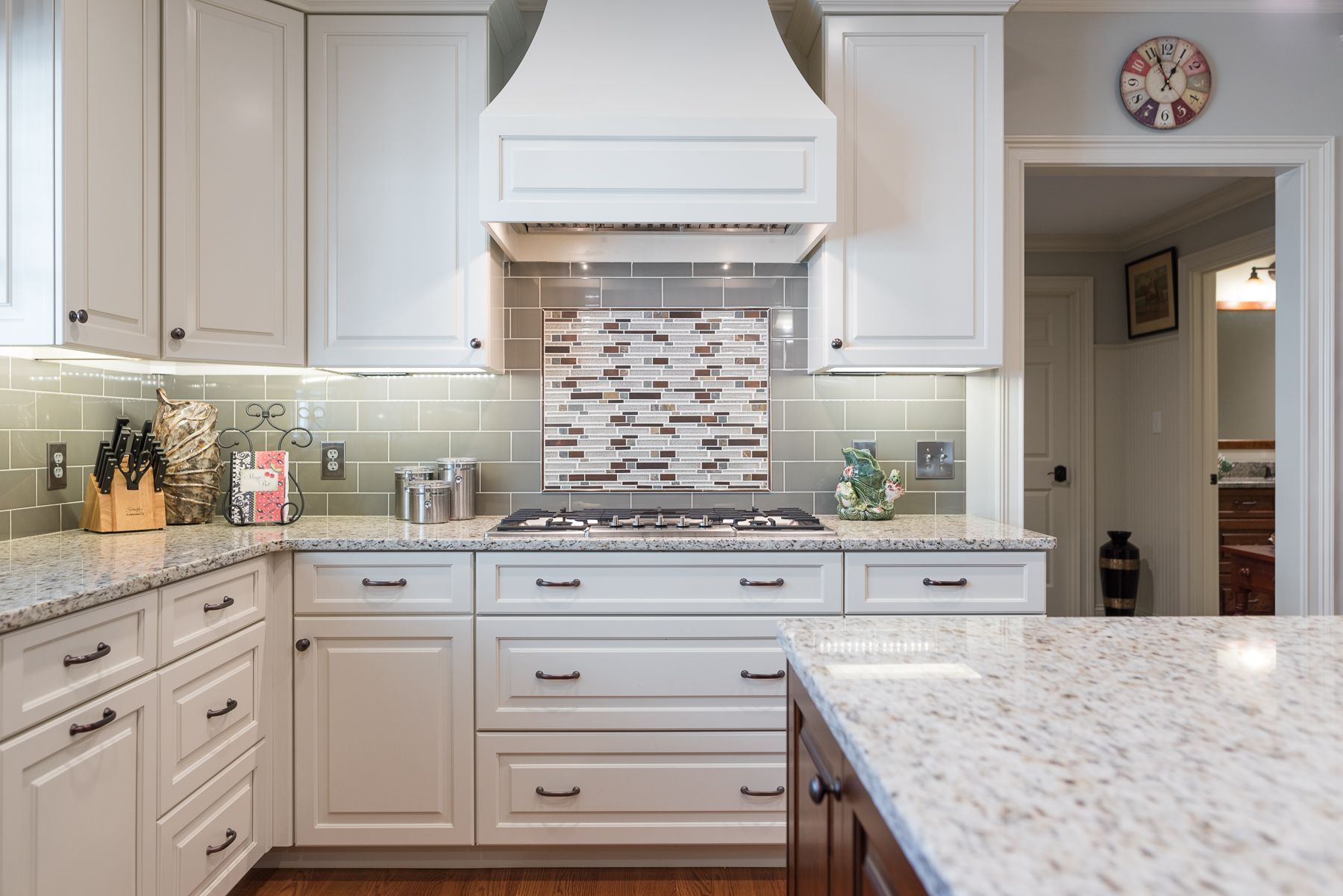 White kitchen with granite countertops, cabinetry, range, and hood.