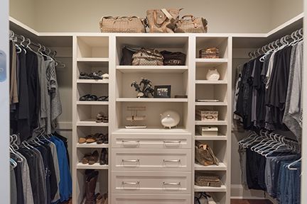Walk-in closet with white shelves and drawers, holding clothes, shoes, and accessories.
