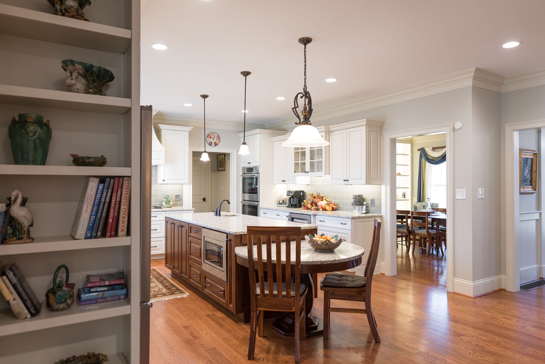 Kitchen with island, round table, wooden cabinets, and built-in bookshelves.