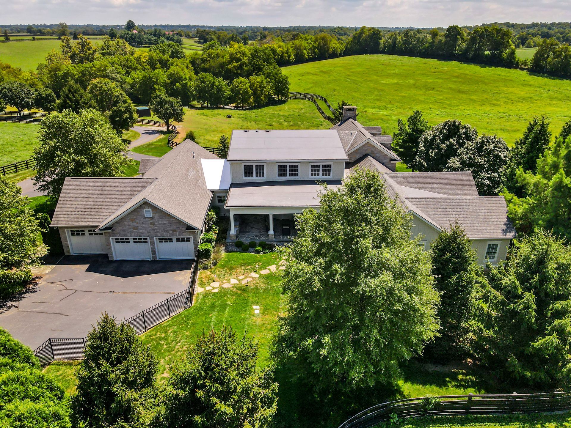 Aerial view of a large farmhouse with green fields and trees.