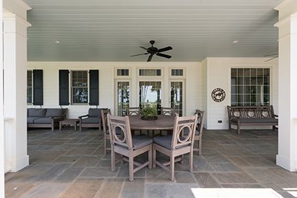 Outdoor dining patio with table, chairs, sofa, and bench under a covered porch.