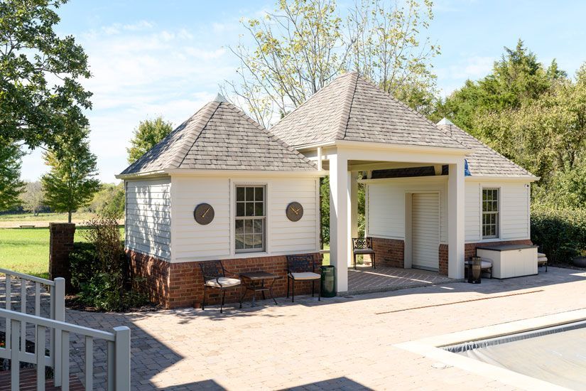 Pool house with white walls, brick base, and covered entrance.