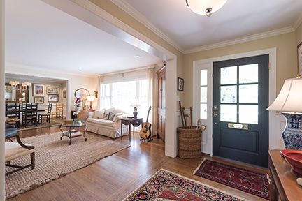 Entryway with dark blue door, rug, and view into living room with a beige couch.