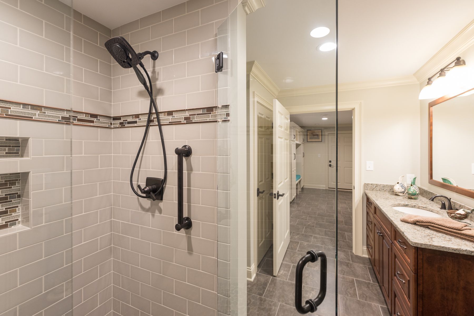 Bathroom with a walk-in shower, dark shower fixtures, and a vanity with a long countertop.