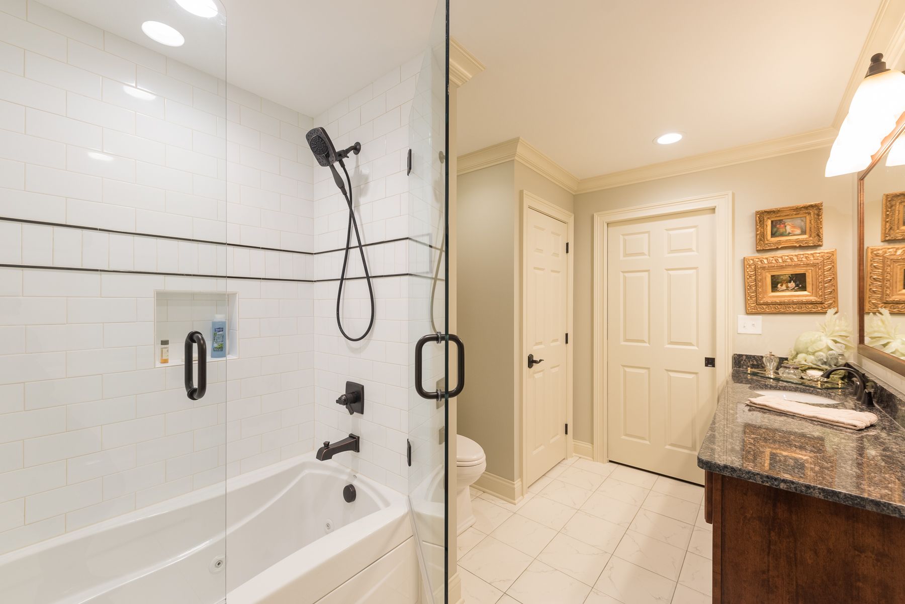 Modern bathroom with a glass shower, vanity, and white tiled walls.