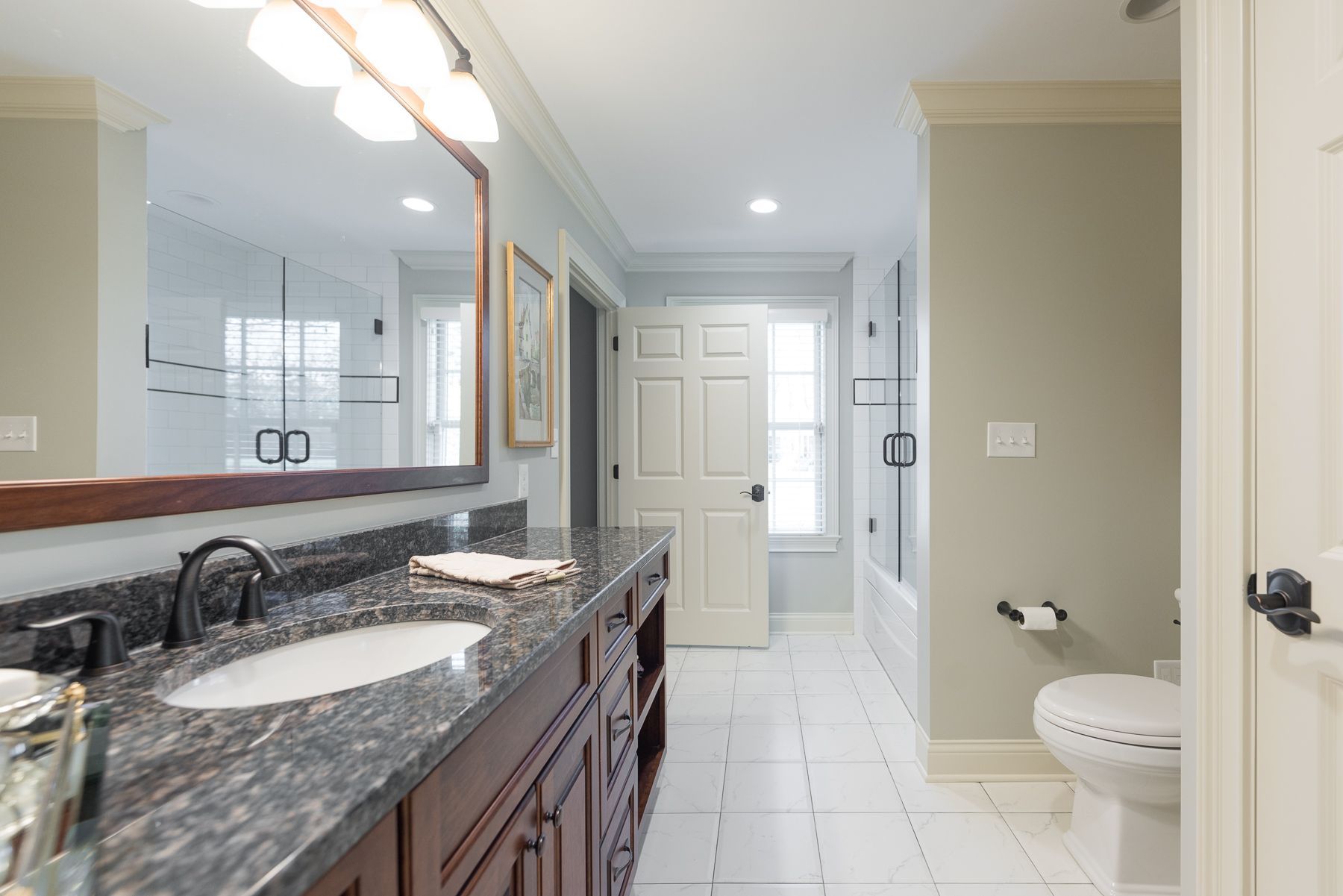 Bathroom with long dark vanity, large mirror, and white tile floor.
