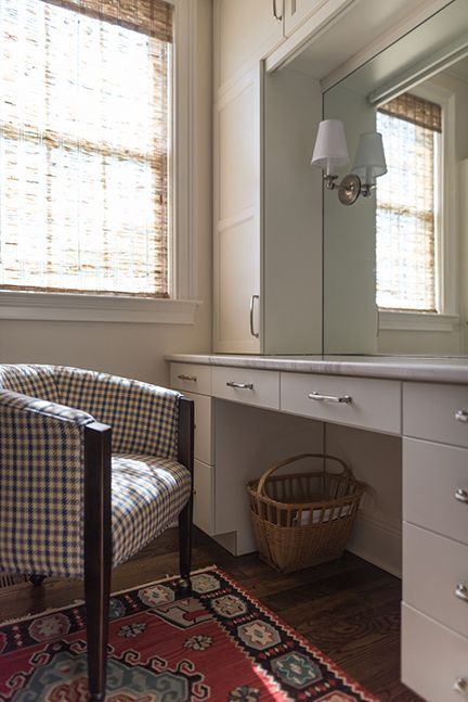 Vanity area with a checkered armchair, white countertop, and woven blinds.
