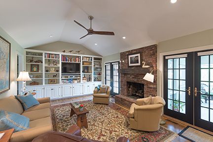 Living room with fireplace, built-in shelves, sofa, and chairs; French doors, neutral colors.