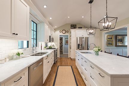 Bright, white kitchen with long island, stainless steel appliances, and light wood floors.
