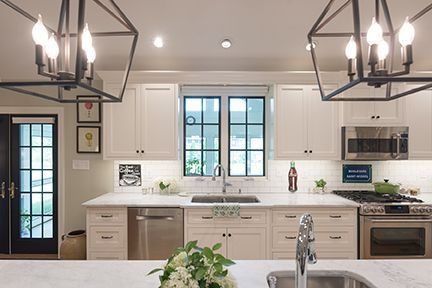Modern kitchen with white cabinets, stainless steel appliances, and black light fixtures.
