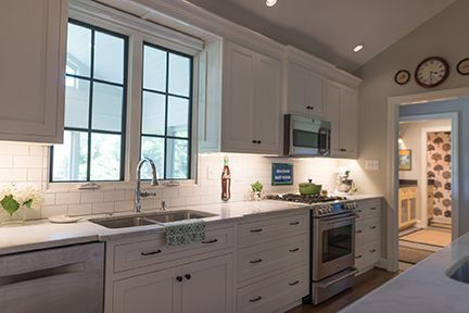White kitchen with window, cabinets, stainless steel appliances, and sink.