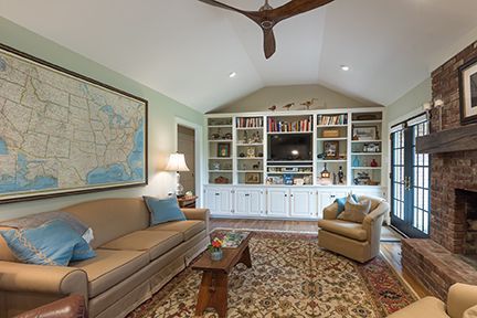 Living room with couch, armchair, bookcase, fireplace, and map on wall.