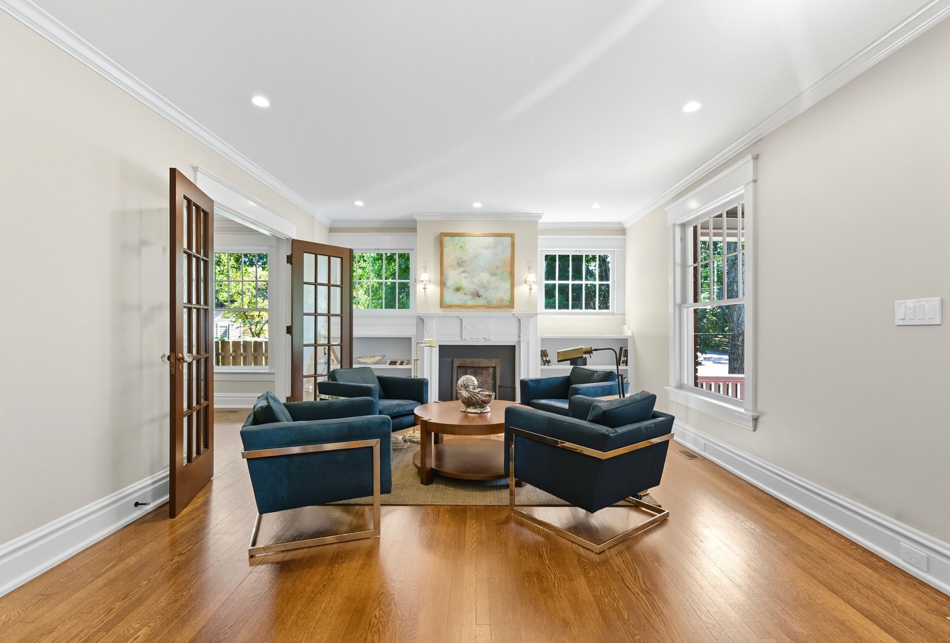 Living room with blue armchairs, hardwood floors, fireplace, and French doors.