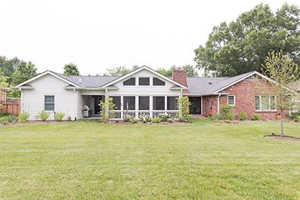 Exterior of a ranch-style house with a large screened porch, red brick, and a green lawn.
