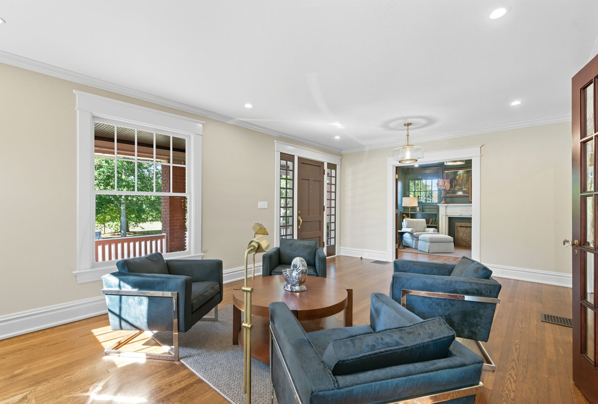 Living room with teal armchairs, a round coffee table, and a window.