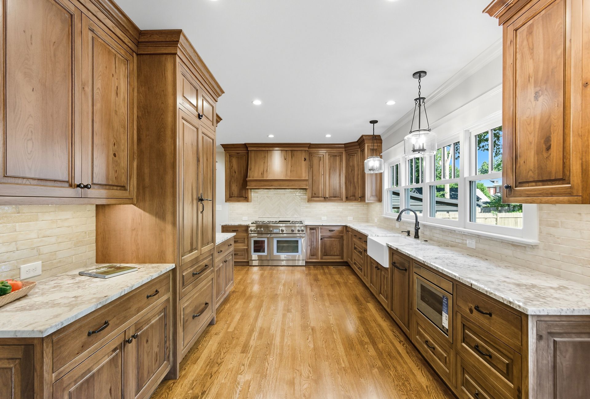 Wooden kitchen with stainless steel appliances, light countertops, and a window.