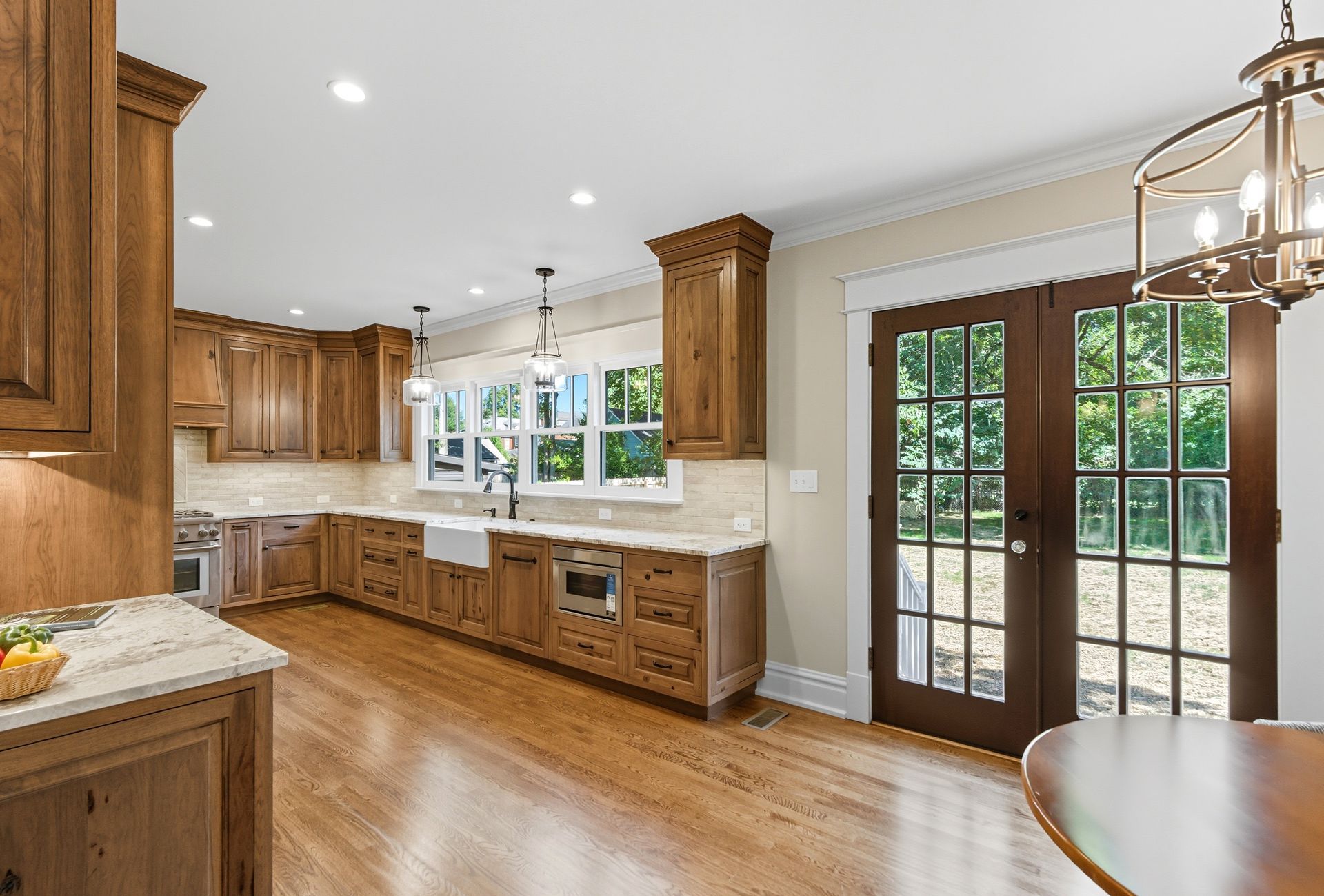 Spacious kitchen with wood cabinets, light countertops, and glass doors leading outside.